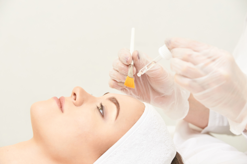 Woman lies down with her hair out of her face while she undergoes a guided chemical peel
