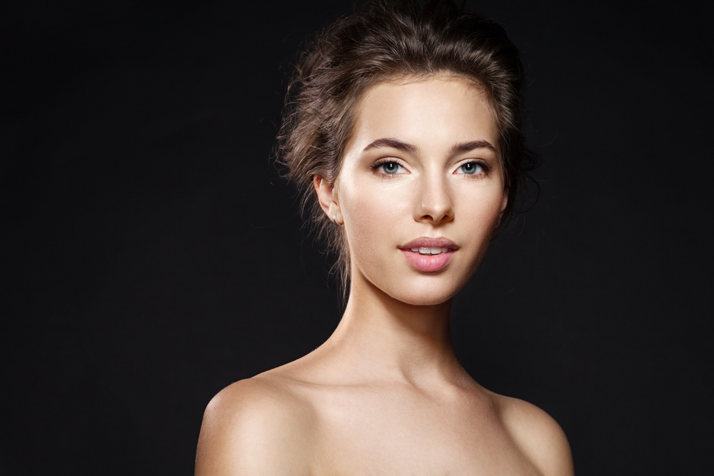 Gorgeous one woman shows off her beautiful lips and teeth while standing in front of a black background.